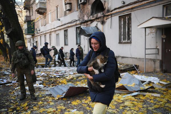دختری به همراه یک گربه در نزدیکی یک ساختمان مسکونی که در اثر گلوله باران نیروهای مسلح اوکراین در دونتسک آسیب دیده است. - اسپوتنیک ایران  
