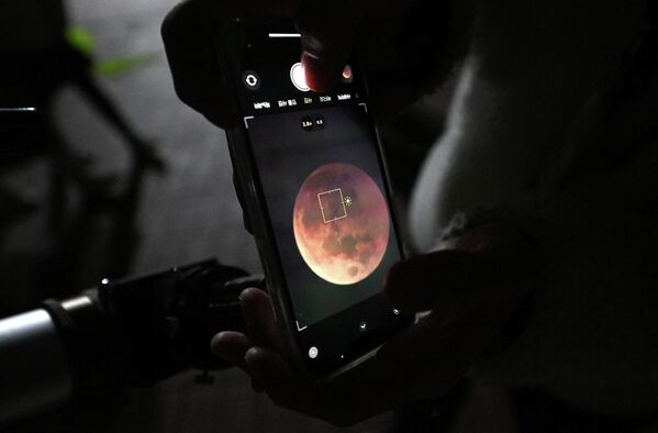 عکس گرفتن مردی با استفاده از گوشی از یک ماه خونی از طریق تلسکوپ در گویانگ، شمال غربی سئول، در 8 نوامبر 2022 - اسپوتنیک ایران  