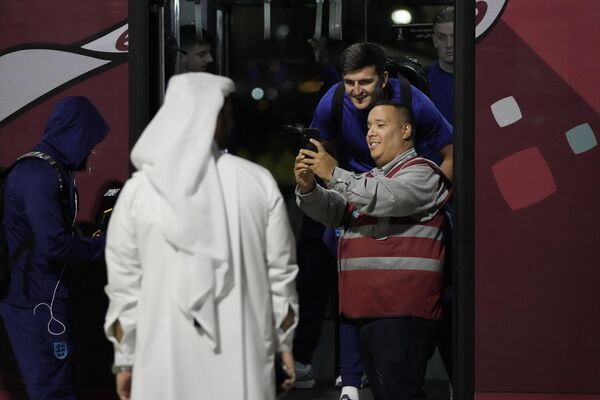 هری مگوایر، سمت راست دوم، از تیم ملی فوتبال انگلیس بعد از رسیدن به فرودگاه «حمد» قطر با هم تیمی هایش با یک کارمند فرودگاه سلفی می گیرد. - اسپوتنیک ایران  