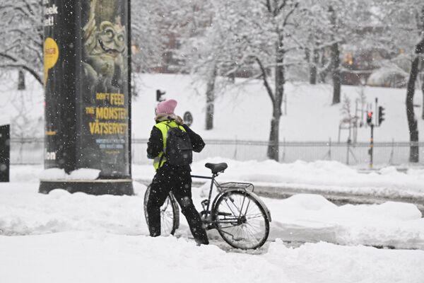 زنی دوچرخه خود را پس از بارش سنگین برف در استکهلم در جنوب سوئد هل می دهد. 21 نوامبر 2022 - اسپوتنیک ایران  