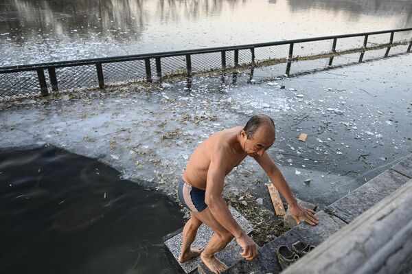 مردی پس از آب تنی در یک دریاچه نیمه یخ زده در پارک شیچاهی در پکن4 دسامبر 2022 - اسپوتنیک ایران  