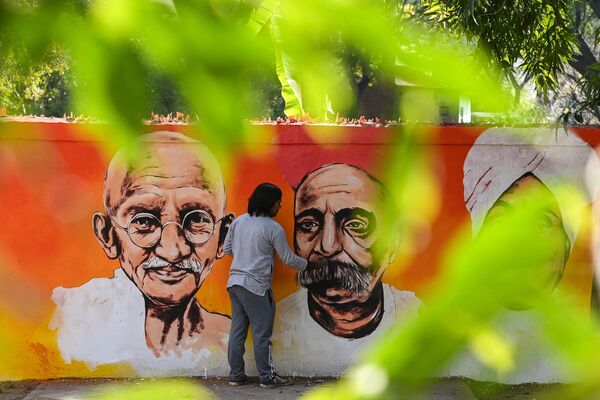 یک هنرمند در 13 فوریه 2022 یک نقاشی دیواری را که چهره‌های برجسته مبارزات آزادی بخش هند از جمله مهاتما گاندی را در دهلی نو به تصویر می‌کشد، به پایان می‌رساند. - اسپوتنیک ایران  