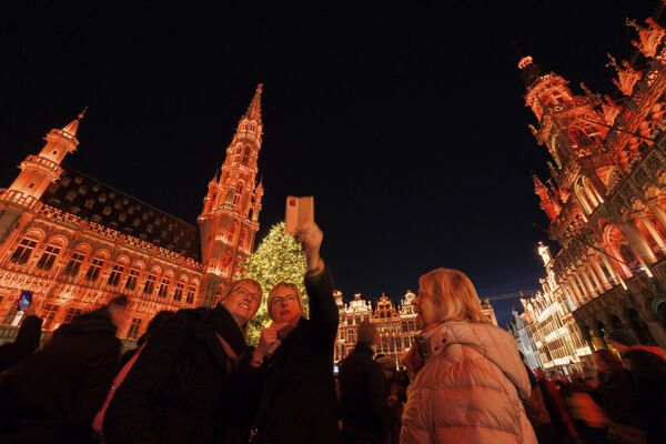 بازدیدکنندگان در مقابل درخت کریسمس روشن در بازار شگفت‌انگیز زمستانی در میدان بزرگ بروکسل، بلژیک  ایستاده‌اند.  - اسپوتنیک ایران  