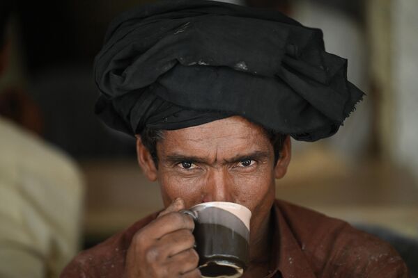 مردی  در 15 ژوئن 2022 در یک رستوران کنار جاده ای در اسلام آباد یک فنجان چای می نوشند.  - اسپوتنیک ایران  