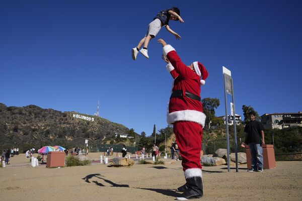 برایان مارتینز، از هالیوود شمالی، با لباس بابا نوئل، با پسرش، براکسون، 4 ساله، در پارک دریاچه هالیوود در لس آنجلس24 دسامبر 2022 - اسپوتنیک ایران  