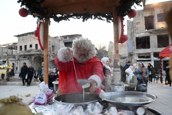 یک مرد سوری با لباس بابا نوئل، در بازار کریسمس در میدان الحطب در شهر شمالی حلب سوریه24 دسامبر 2022 - اسپوتنیک ایران  