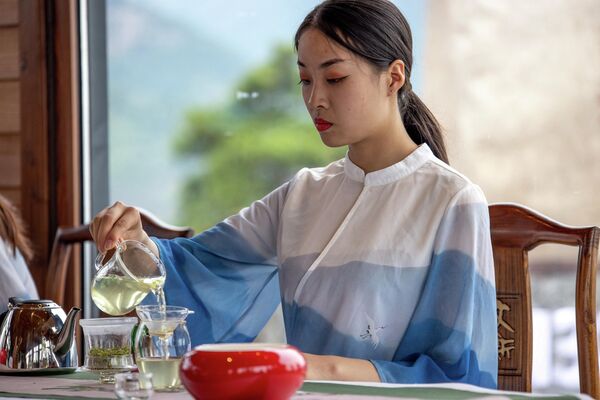 مراسم چای چینی یک فلسفه و فرهنگ خاص است که از دوران باستان سرچشمه گرفته است. چینی ها فقط به آرامی چای نمی نوشند، بلکه از آن لذت می برند، عطر آن را استشمام می کنند، طعم و تغییر رنگ نوشیدنی را در فرآیند دم کردن احساس می کنند. در تصویر: زنی در حال ریختن چای. - اسپوتنیک ایران  