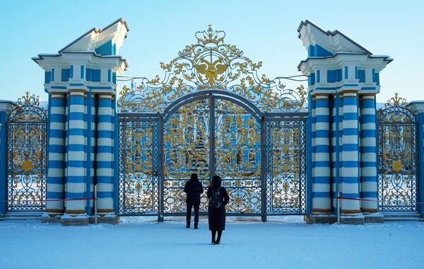 خانم و آقایی در کنار دروازه &quot;کاخ کاترین&quot; در محوطه موزه دولتی&quot; تزارسکویه سلو&quot; در شهر پوشکین ایستاده اند. - اسپوتنیک ایران  