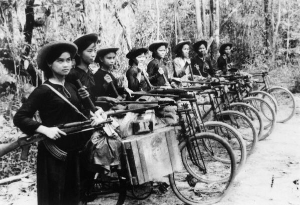 تصویر گرفته شده در مارس 1970 سربازان زن را نشان می دهد که اسلحه و مهمات را با دوچرخه برای ارتش ویت کنگ ها (جببه آزادی بخش ملی ویتنام جنوبی)  و ویتنام شمالی در بین لانگ، منطقه جنوب شرقی ویتنام حمل می کنند - اسپوتنیک ایران  