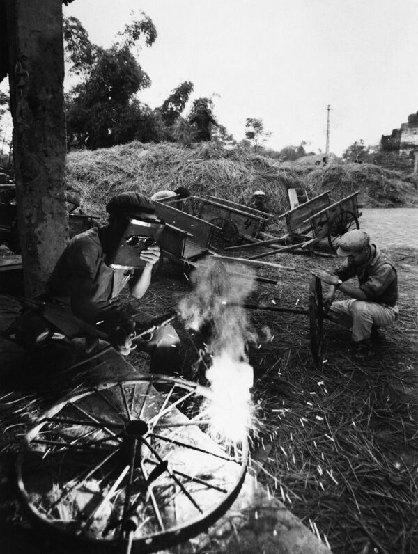 کارگران در آوریل 1968 در ویتنام شمالی برای تعمیر  چرخ‌های گاری‌های شالیکاری  کار می‌کنند - اسپوتنیک ایران  
