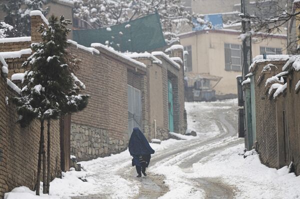 یک زن برقع پوش هنگام بارش برف در کابل در امتداد خیابانی قدم می زند.11 ژانویه 2023 - اسپوتنیک ایران  