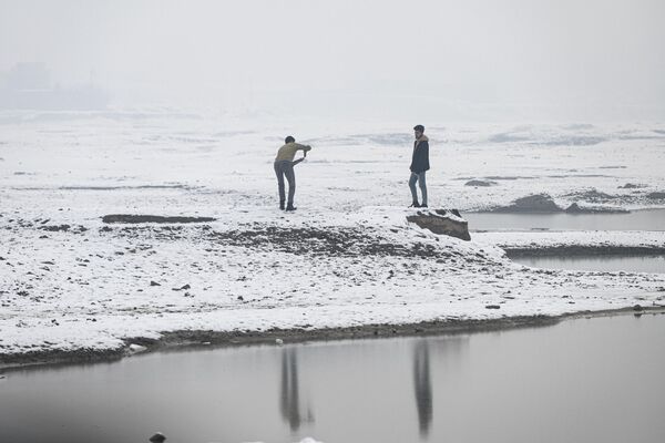 مردان افغان هنگام بارش برف در کنار دریاچه قرغه کابل8 ژانویه 2023 - اسپوتنیک ایران  