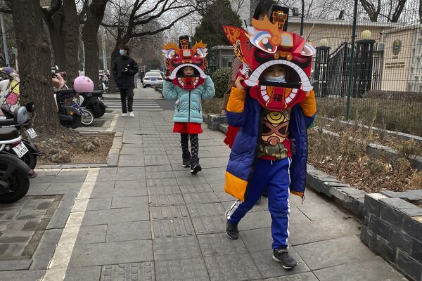 کودکانی که ماسک های رقص شیر مقوایی روی سر گذاشته اند در خیابانی در پکن قدم می زنند. - اسپوتنیک ایران  