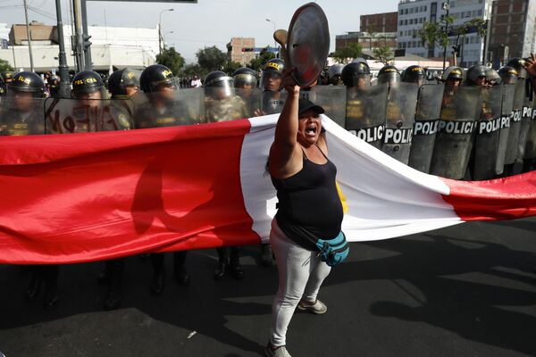 یک معترض ضد دولتی در مقابل پلیس که مانع از راهپیمایی علیه رئیس جمهور دینا بولوارته در لیما، پرو، روز پنجشنبه، 19 ژانویه 2023 می شود، ایستاده است.  - اسپوتنیک ایران  