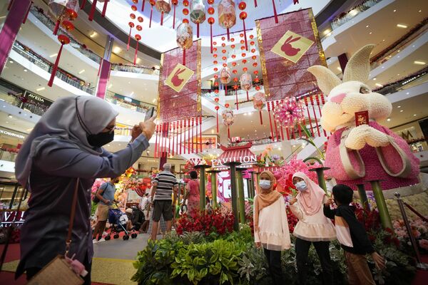 زنی ز فرزندان خود ر مقابل تزئینات سال نو در مرکز خریدی در کوالالامپور عکس می گیرد. - اسپوتنیک ایران  