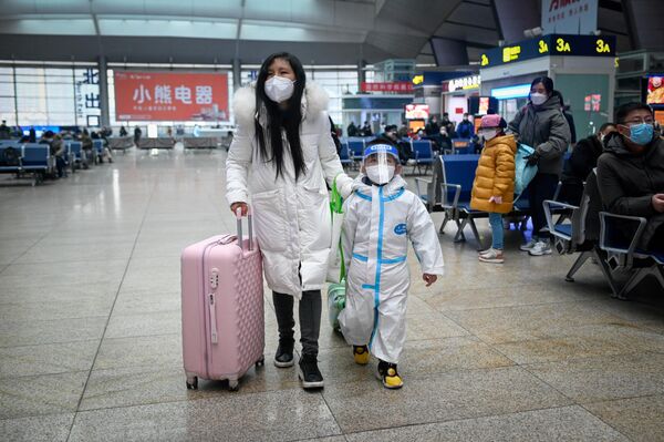 زنی با فرزندش با وسایل محافظت شخصی داخل ایستگاه قطار در پکن .12 ژانویه مهاجرت سالانه شروع می شود، زمانی  که مردم به شهرهای محل تولد خود بر می گردند ا سال نو قمری را جشن بگیرند. - اسپوتنیک ایران  