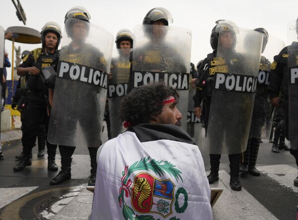 مردی در خیابان و در هنگام راهپیمایی علیه دینا بولوارته، رئیس جمهور پرو در لیما، روز سه شنبه 17 ژانویه 2023، در مقابل نیروهای ضد شورش در خیابان نشسته است. معترضان به دنبال انتخابات فوری، استعفای بولوارته، آزادی پدرو کاستیو رئیس جمهور مخلوع و احرای عدالت برای ده ها معترض کشته شده در درگیری با پلیس هستند.  - اسپوتنیک ایران  