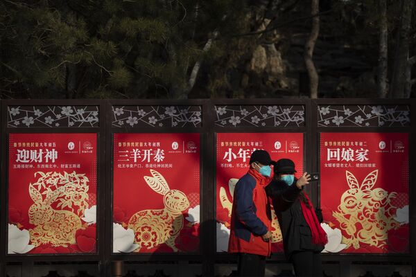بازدیدکنندگانی که ماسک به چهره دارند، در اولین روز تعطیلات سال نو قمری، یکشنبه، 22 ژانویه 2023، در مقابل ردیفی از بیلبوردهای با مضمون سال خرگوش در یک پارک عمومی در پکن ژست می گیرند. - اسپوتنیک ایران  