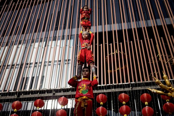 آکروبات های جوان در حین اجرای نمایشی در آستانه سال نو قمری در منطقه محله چینی بانکوک در 21 ژانویه 2023 یک برج انسانی تشکیل می دهند. - اسپوتنیک ایران  