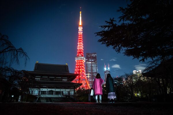 مردم از معبد زوجی دیدن می کنند زیرا برج توکیو برای جشن سال نو قمری چینی در توکیو در 21 ژانویه 2023 به رنگ قرمز روشن می شود. - اسپوتنیک ایران  