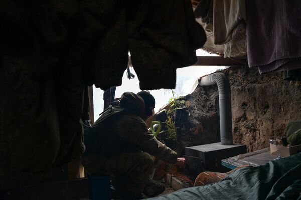 یکی از اعضای تیپ قطب شمال اجاقی را در محل زندگی سربازان در بخش جنوبی عملیات ویژه نظامی روشن می کند. - اسپوتنیک ایران  