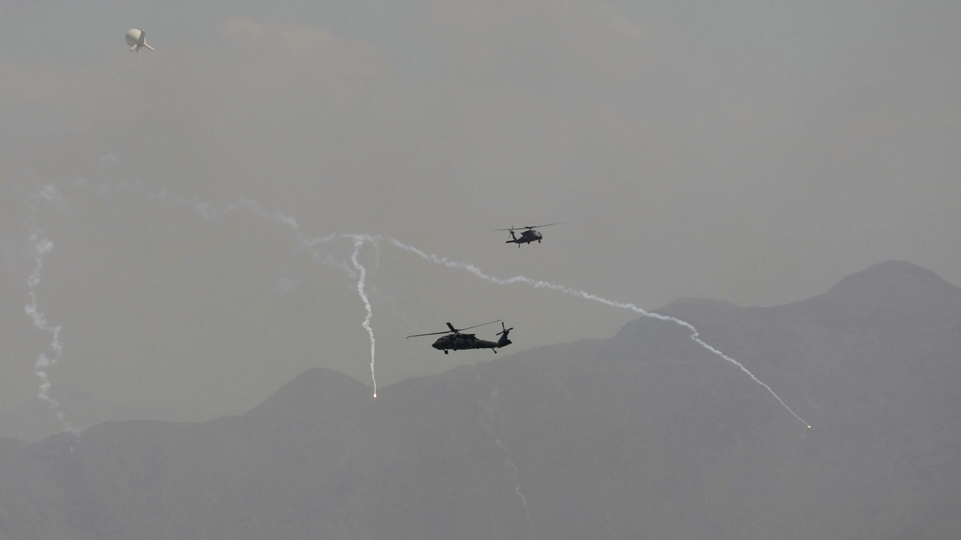 Anti-missile decoy flares are deployed as U.S. Black Hawk military helicopters and a dirigible balloon fly over the city of Kabul, Afghanistan, Sunday, Aug. 15, 2021. - اسپوتنیک ایران  , 1920, 25.01.2023