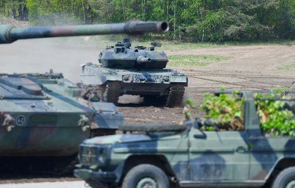از بایگانی--این عکس بایگانی شده که در تاریخ 20 مه 2019 گرفته شده است، یک تانک جنگی اصلی لئوپارد 2 A7 (پس زمینه) نیروهای مسلح آلمان را نشان می‌دهد که در تمرین آموزشی &quot;نیروی ضربتی مشترک آمادگی بسیار بالا&quot; (VJTF) به عنوان بخشی از نیروهای  ناتو شرکت می‌کند. واحد تانکی در منطقه آموزش نظامی در مونستر، شمال آلمان. - آلمان در 25 ژانویه 2023 پس از هفته ها فشار کیف و بسیاری از متحدانش، تحویل تانک های لئوپارد 2 به اوکراین را تایید کرد. سخنگوی دولت این کشور در بیانیه ای گفت که برلین یک مجموعه متشکل از 14 تانک Leopard 2 A6 را از ذخایر ارتش آلمان را در اختیار کیف قرار خواهد داد و همچنین به سایر کشورهای اروپایی مجوز ارسال تانک از ذخایر خود به اوکراین را می دهد.(عکس از PATRIK STOLLARZ / AFP) - اسپوتنیک ایران  