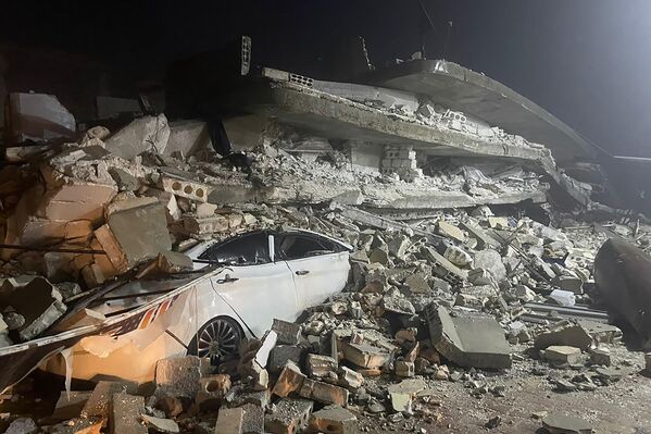 خودرویی که در شهرک ازمارین در استان ادلب در شمال سوریه زیر آوار ساختمان فروریخته  مانده است. - اسپوتنیک ایران  