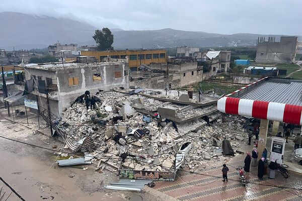 مردم در جستجوی آوارهای ساختمان فروریخته در شهر ازمارین در استان ادلب در شمال سوریه هستند. - اسپوتنیک ایران  