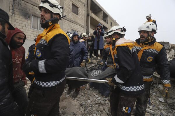  اعضای دفاع مدنی سوریه، معروف به کلاه سفیدها، فردی را حمل می کند که پس از زلزله 6 فوریه در شهر زردان در حومه شمال غربی ادلب سوریه از زیر آوار نجات یافته است. - اسپوتنیک ایران  