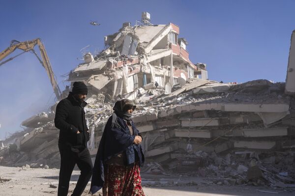 ساکنان محلی در مقابل ساختمان ویران شده در نورداگی در جنوب شرقی ترکیههزاران نفر که در جریان زلزله فاجعه بار ترکیه و سوریه خانه های خود را از دست دادند. - اسپوتنیک ایران  