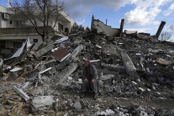 در حالی که تیم‌های امداد اضطراری به دنبال افراد زیر بقایای ساختمان‌های ویران شده در شهر نورداگی در حومه شهر عثمانیه در جنوب ترکیه هستند، یک زن روی آوار نشسته است. - اسپوتنیک ایران  