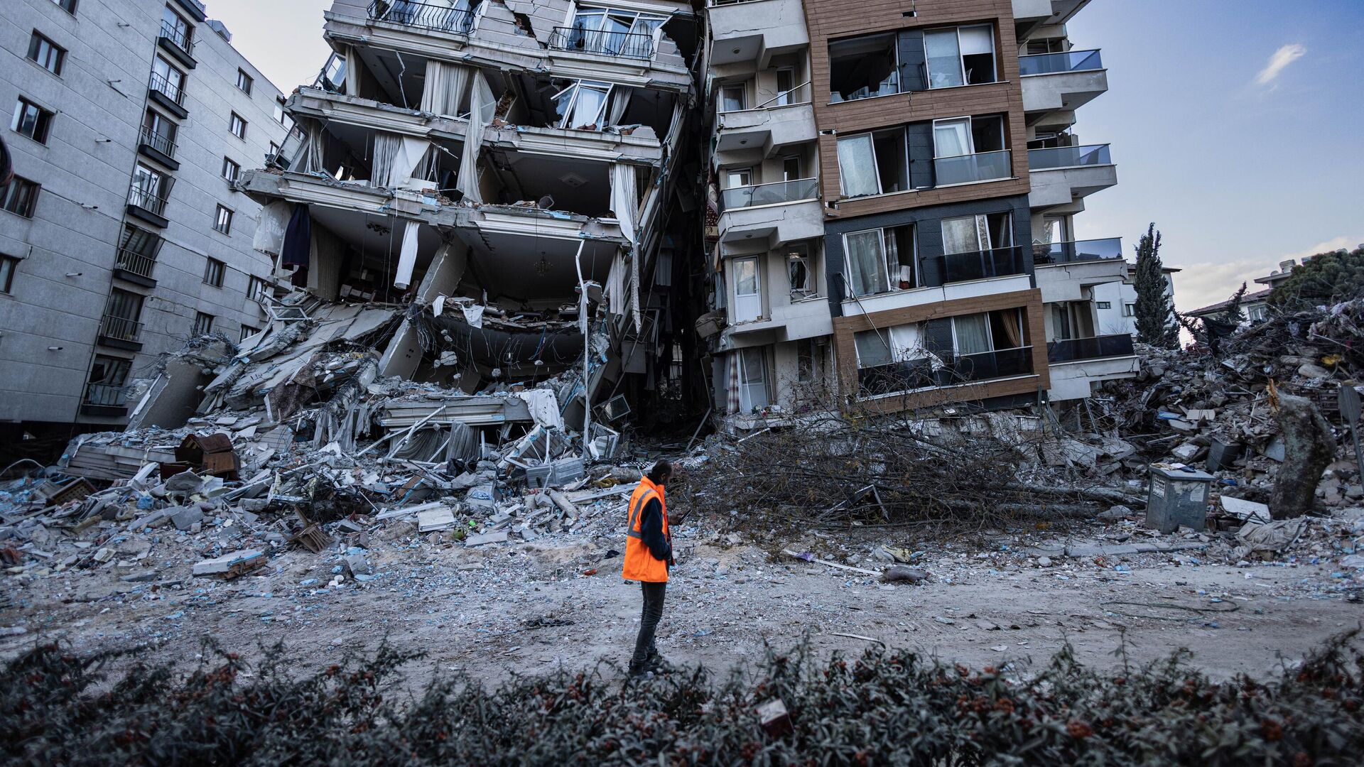 Спасатель проходит мимо частично разрушенных в результате землетрясений зданий в городе Антакья, Турция - اسپوتنیک ایران  , 1920, 27.02.2023