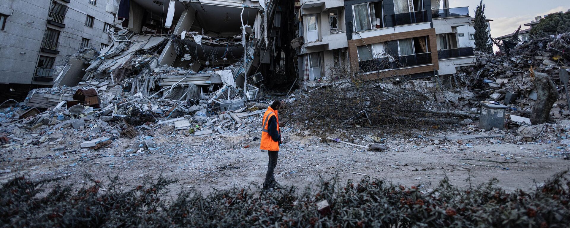Спасатель проходит мимо частично разрушенных в результате землетрясений зданий в городе Антакья, Турция - اسپوتنیک ایران  , 1920, 27.02.2023