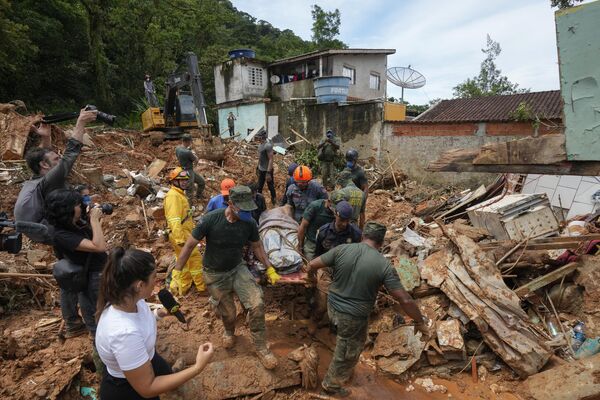 نیروهای امداد رسانی و داوطلبان پس از باران شدید در شهر ساحلی سائو سباستیائو برزیل، جسد یک قربانی را در نزدیکی ساحل بارا دو ساهی حمل کردند. - اسپوتنیک ایران  