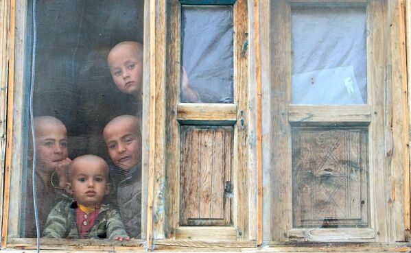 پسران افغانستانی از پنجره خانه خود در منطقه  یفتل سفلی استان  بدخشان به بیرون نگاه می کنند. - اسپوتنیک ایران  