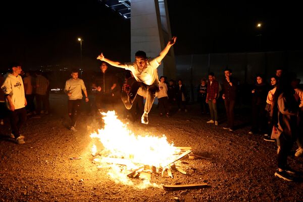یک ایرانی در حال پریدن از آتش در مراسم چهارشنبه سوری.ایرانی ها غروب آخرین سه شنبه  سال را با  مراسم آتش بازی جشن می گیرند. - اسپوتنیک ایران  