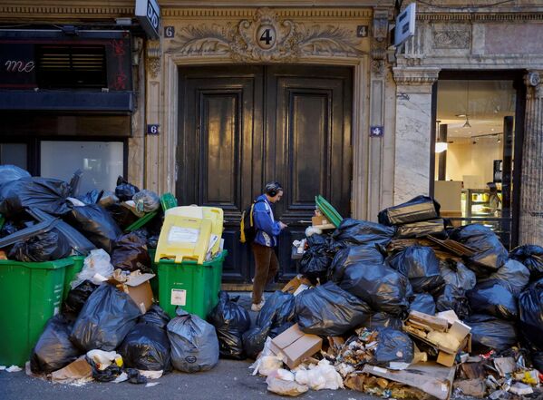 مردی در 20 مارس 2023 در پاریس از کنار انبوهی از کیسه های زباله می گذرد که از زمان اعتصاب کارگران جمع آوری زباله علیه اصلاحات پیشنهادی دولت فرانسه در حقوق بازنشستگی در پاریس در 20 مارس 2023 انباشته شده است.  - اسپوتنیک ایران  