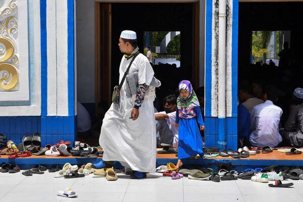 مردی و دخترش هنگام نماز در روز دوم ماه مبارک رمضان در شهر تاگویگ در حومه مانیل در 24 مارس 2023 از مقابل یک مسجد راه می روند. - اسپوتنیک ایران  