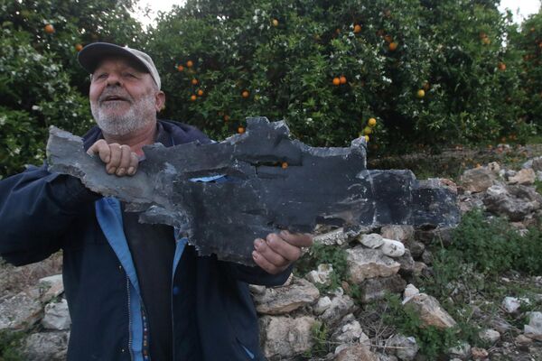 مردی در پی حملات هوایی اسرائیل در القلیله، در حومه شهر صور، در جنوب بیروت، پایتخت لبنان در 7 آوریل 2023، یک ترکش موشک در دست دارد. - اسپوتنیک ایران  