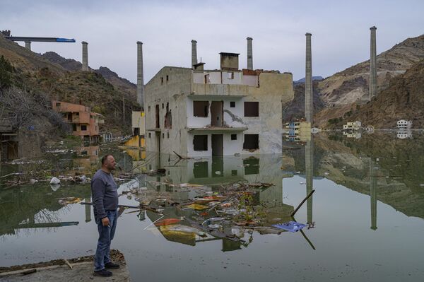 یک ساکن محلی به شهر خود می نگرد که توسط یک دریاچه مصنوعی ناشی از سدی که جریان رودخانه کوروه (که به آن چورخی نیز گفته می شود) در یوسفلی، استان آرتوین، در شمال شرقی ترکیه، در 4 آوریل 2023 زیر آب رفته است.  - اسپوتنیک ایران  