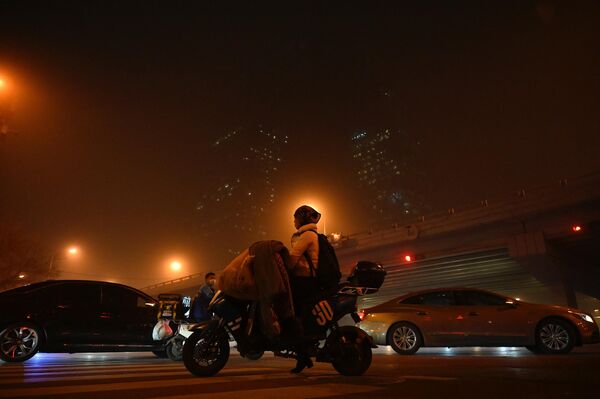 زنی در 10 آوریل 2023 در طول طوفان شن در پکن، سوار بر اسکوتر از منطقه تجاری مرکزی می گذرد. - اسپوتنیک ایران  