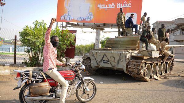 Мужчина поднимает руку в знак поддержки, проезжая мимо солдат суданской армии, занимающих позицию в городе Порт-Судан, Судан - اسپوتنیک ایران  