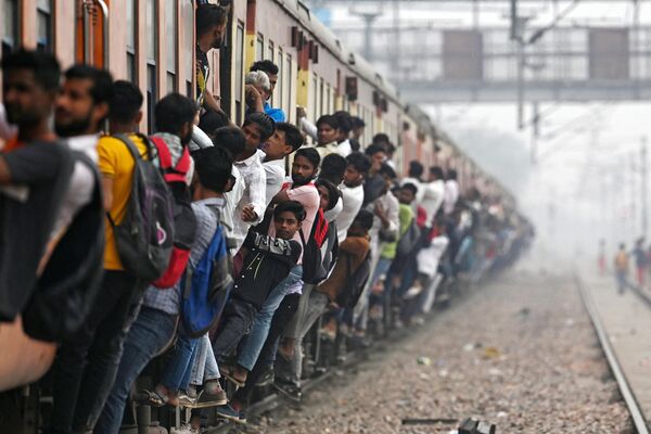 مسافران در 24 آوریل 2023 با قطاری پرجمعیت در نزدیکی ایستگاه راه آهن در شهر لونی در ایالت اوتار پرادش هند سفر می کنند. - اسپوتنیک ایران  