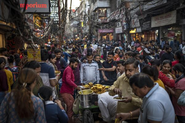 در حالی که خریداران در بازاری در دهلی نو، هند، شنبه، 12 نوامبر 2022، ازدحام می کنند، مردم غذاهای خیابانی می خورند. - اسپوتنیک ایران  