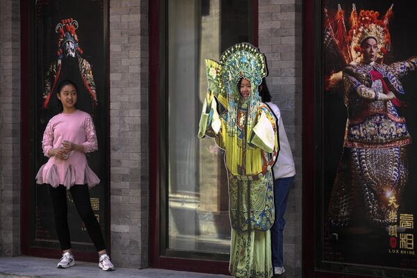 بازدیدکنندگان برای یک عکس یادگاری با یک ماکت اپرای چینی در خارج از مغازه ای در خیابان کیانمن ژست می گیرند. پکن، دوشنبه، 1 مه 2023  - اسپوتنیک ایران  