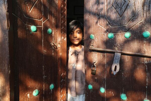 نگاهی از لای در. دختر ایرانی در بین دو لنگه درب خانه ای در جزیره قشم. - اسپوتنیک ایران  