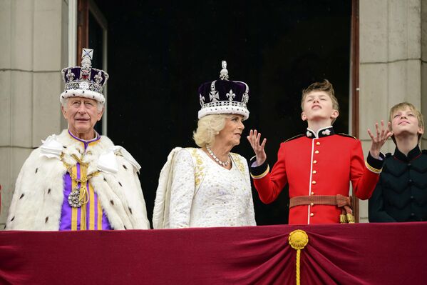 پادشاه بریتانیا، چارلز سوم، سمت چپ، و ملکه کامیلا، در کنار او، پس از تاجگذاری خود، در لندن، شنبه، 6 مه 2023، از بالکن کاخ باکینگهام به بیرون نگاه می کنند. (لئون نیل/عکس از استخر از طریق AP) - اسپوتنیک ایران  