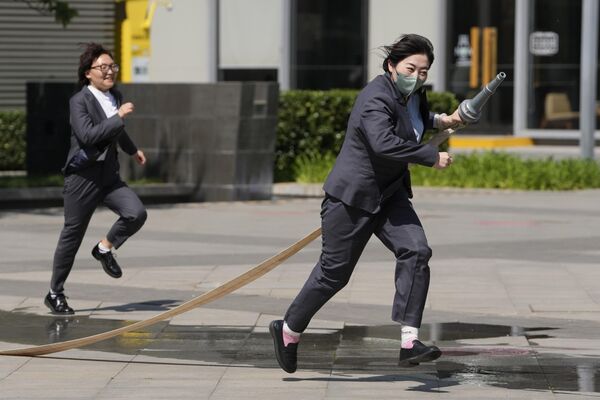 کارگران در خارج از ساختمان اداری در پکن، دوشنبه، 8 مه 2023، مهارت های آتش نشانی خود را آزمایش می کنند. (AP Photo/Ng Han Guan) - اسپوتنیک ایران  