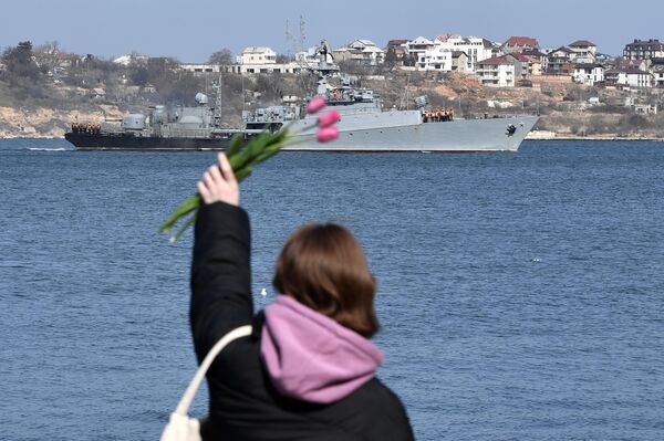 دختری از ساحل به سمت یک کشتی نظامی در سواستوپل دست تکان می دهد. - اسپوتنیک ایران  